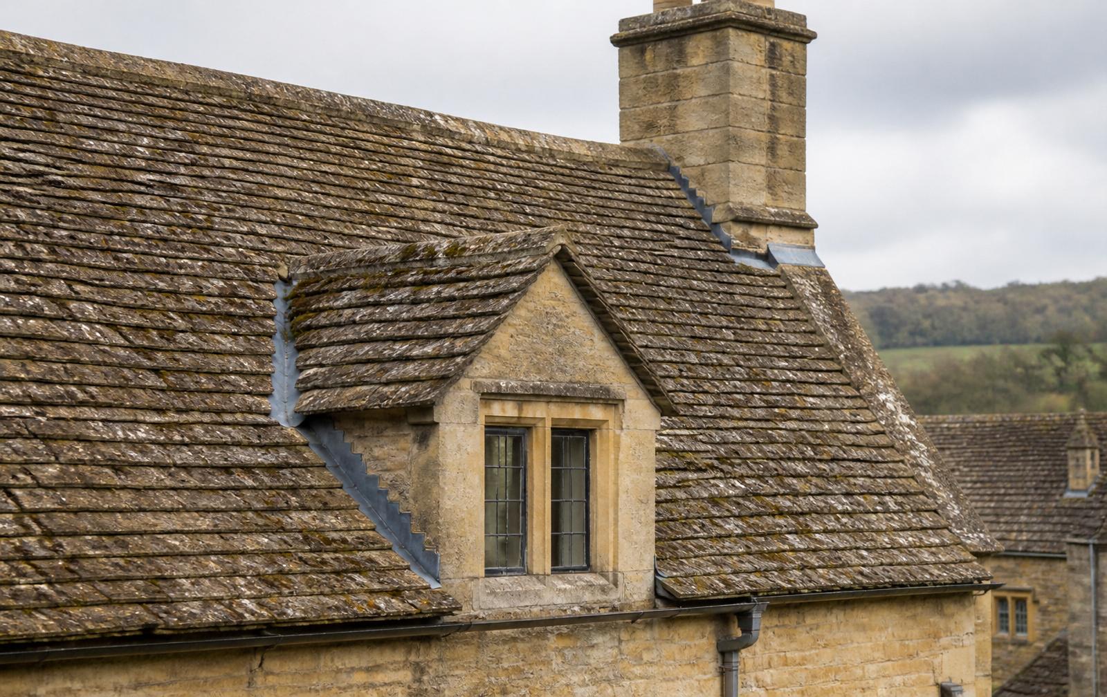 Traditional honey-coloured Cotswold stone tile roof with stone dormer, lead flashings and stone chimney — heritage roofing by White Horse Roofing Services, Oxfordshire & Cotswolds
